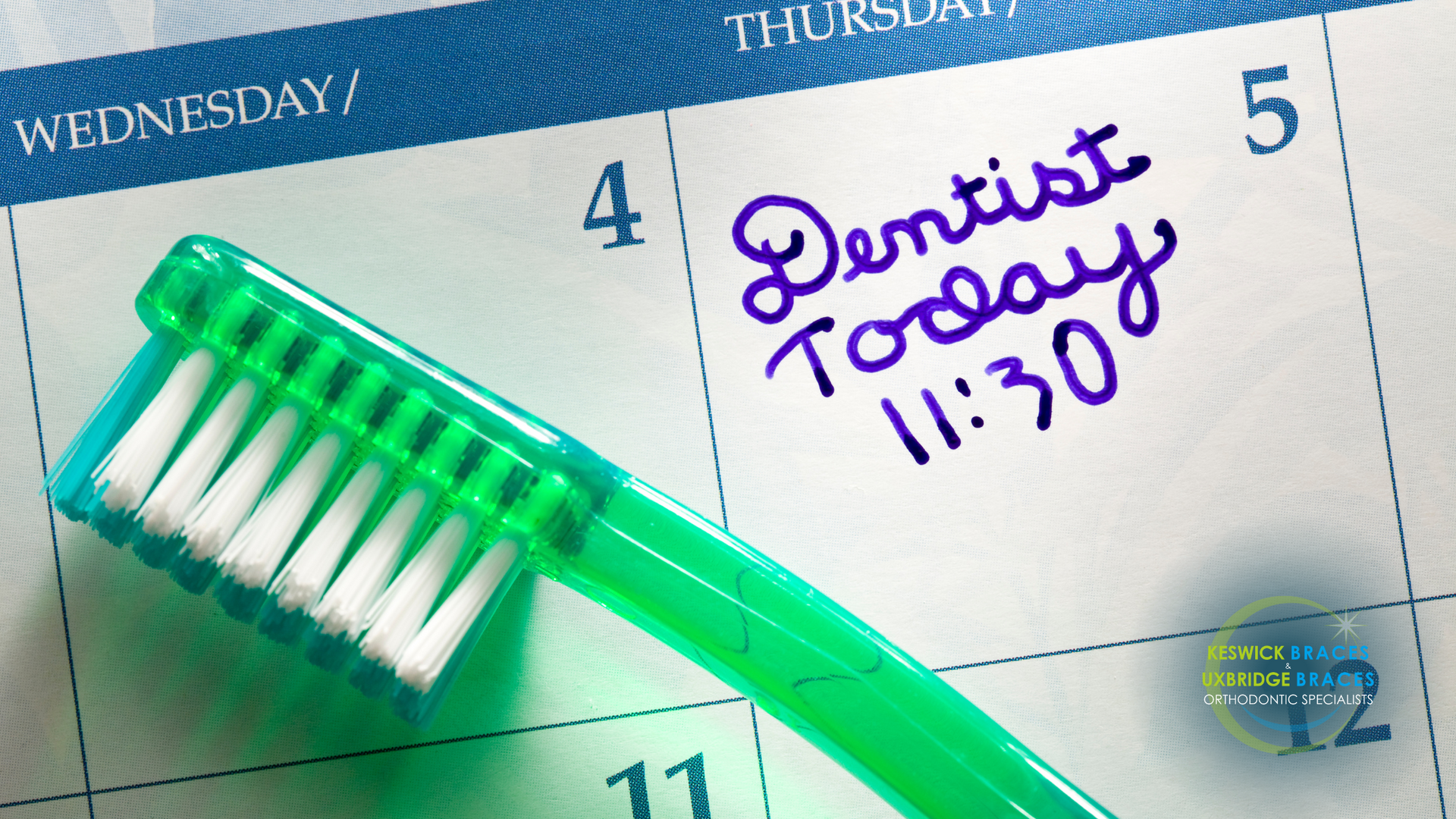 A green toothbrush is sitting on top of a calendar that says dentist today