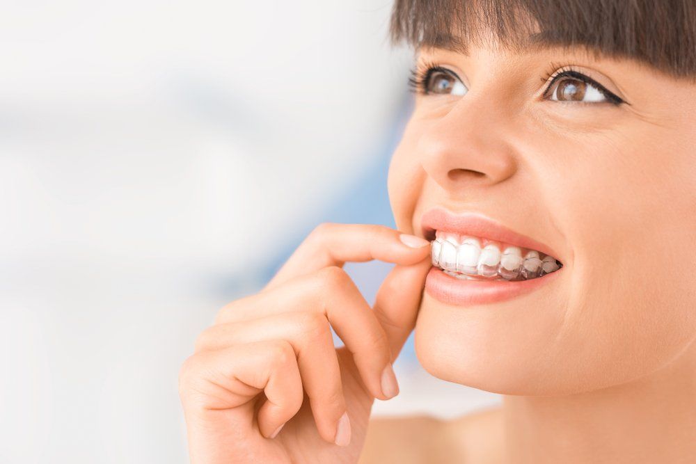 Orthodontist in Keswick and Uxbridge | Invisalign in Keswick and Uxbridge | Invisalign | Invisalign Teen | woman smiling putting on Invisalign