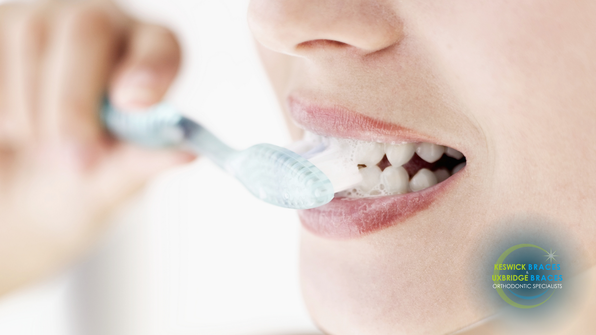 A woman is brushing her teeth with a blue toothbrush.