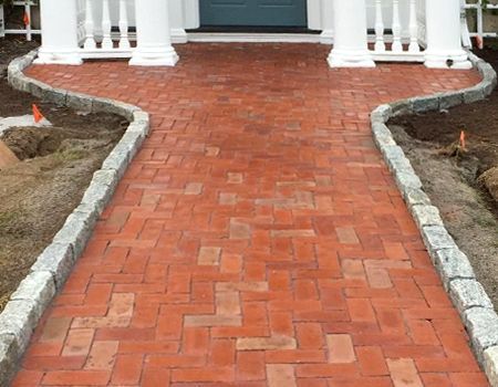 A red brick walkway leading to the front door of a house.