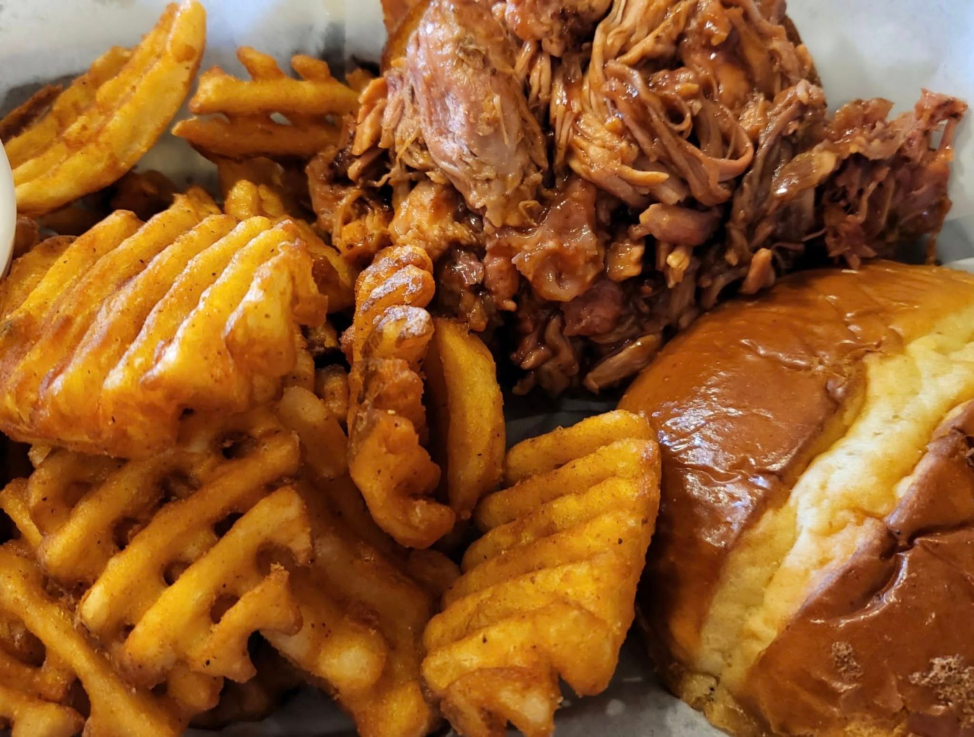 Pulled pork with waffle fries and a bun.