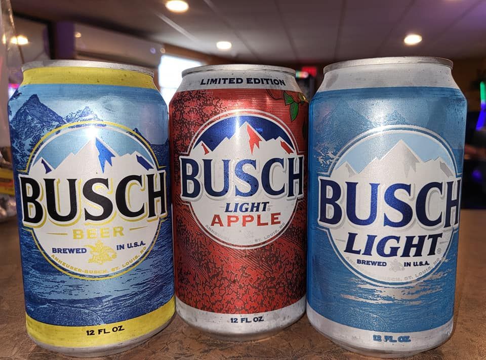 Three Busch beer cans: original, apple, and light blue, displayed on a surface.