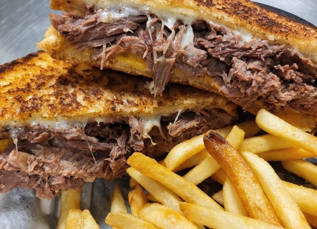 Shredded meat sandwich with melted cheese and fries, on a plate.