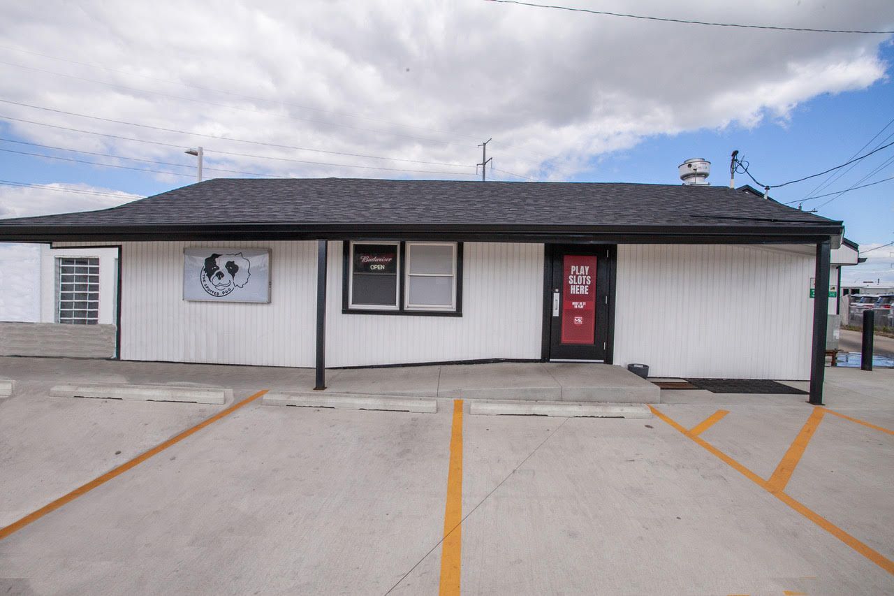 White building with black trim, parking in front. Red door.