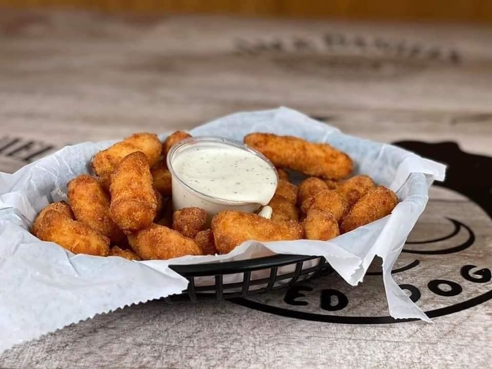 Basket of fried cheese curds with a cup of dipping sauce.