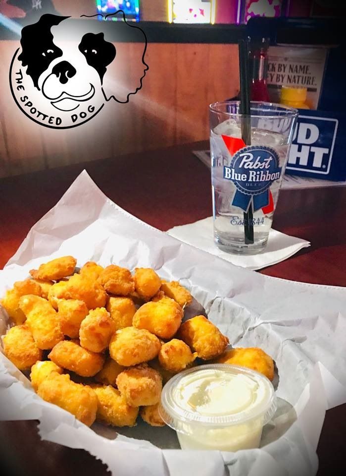Basket of fried cheese curds with dipping sauce at The Spotted Dog bar, next to a PBR glass.