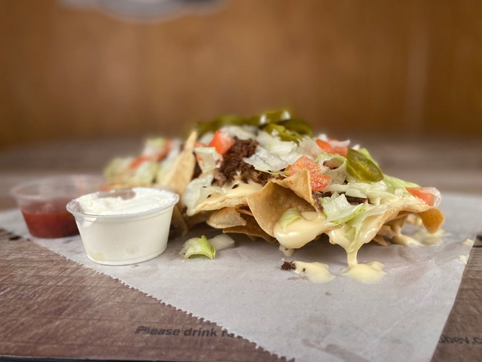 Nachos with cheese, lettuce, jalapeños, and meat, served with salsa and sour cream.