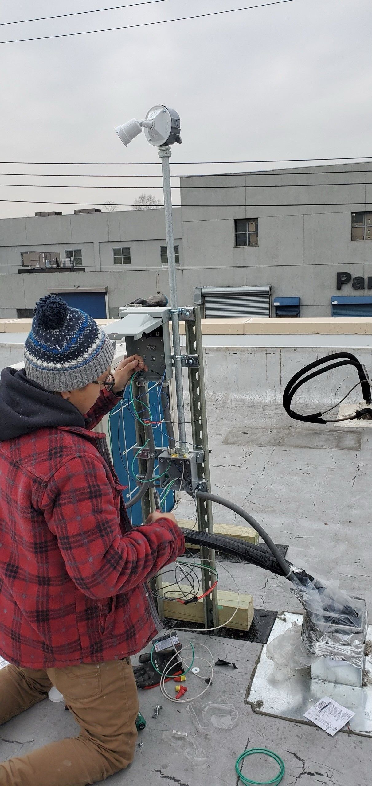 A man is kneeling down on the ground working on a roof.