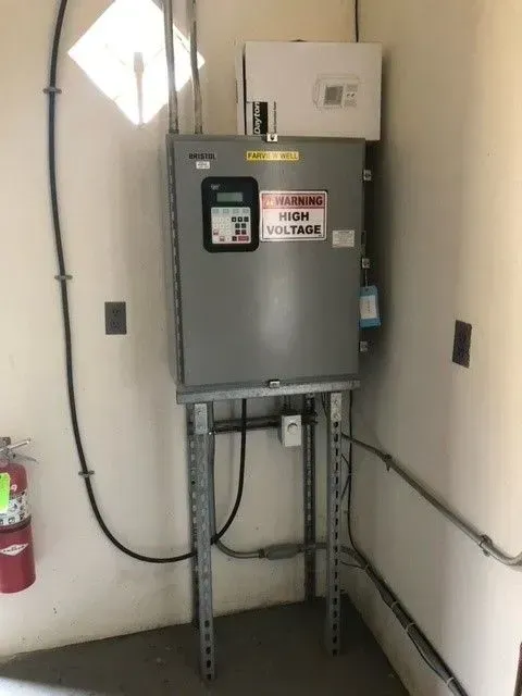 A voltage box is sitting on a metal stand in a room.