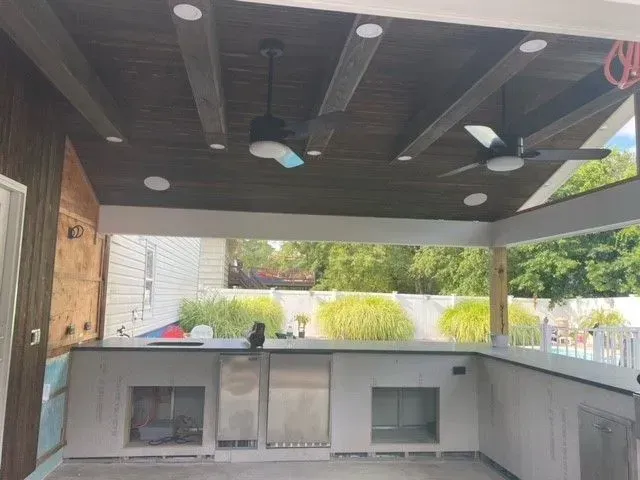 A ceiling fan is hanging from the ceiling of an outdoor kitchen.