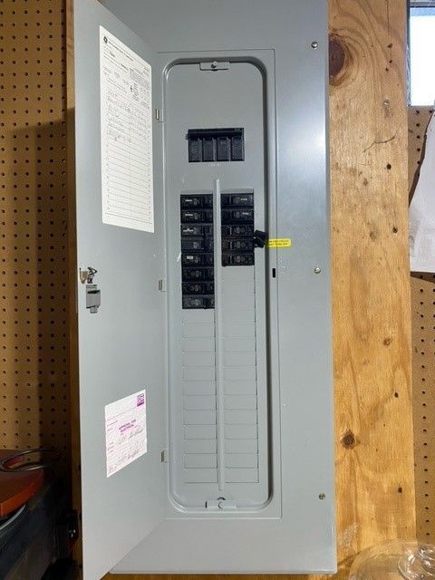 A electrical box with the door open is sitting on a wooden wall.