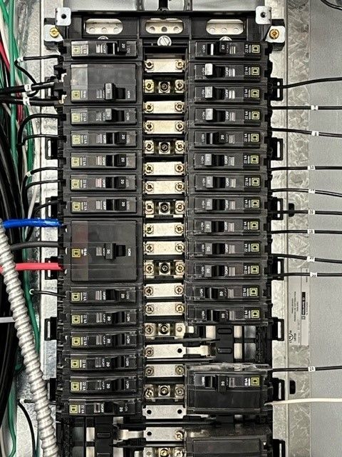 A close up of a electrical panel with a lot of wires coming out of it.