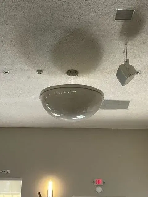 A room with a ceiling light and speakers hanging from it.