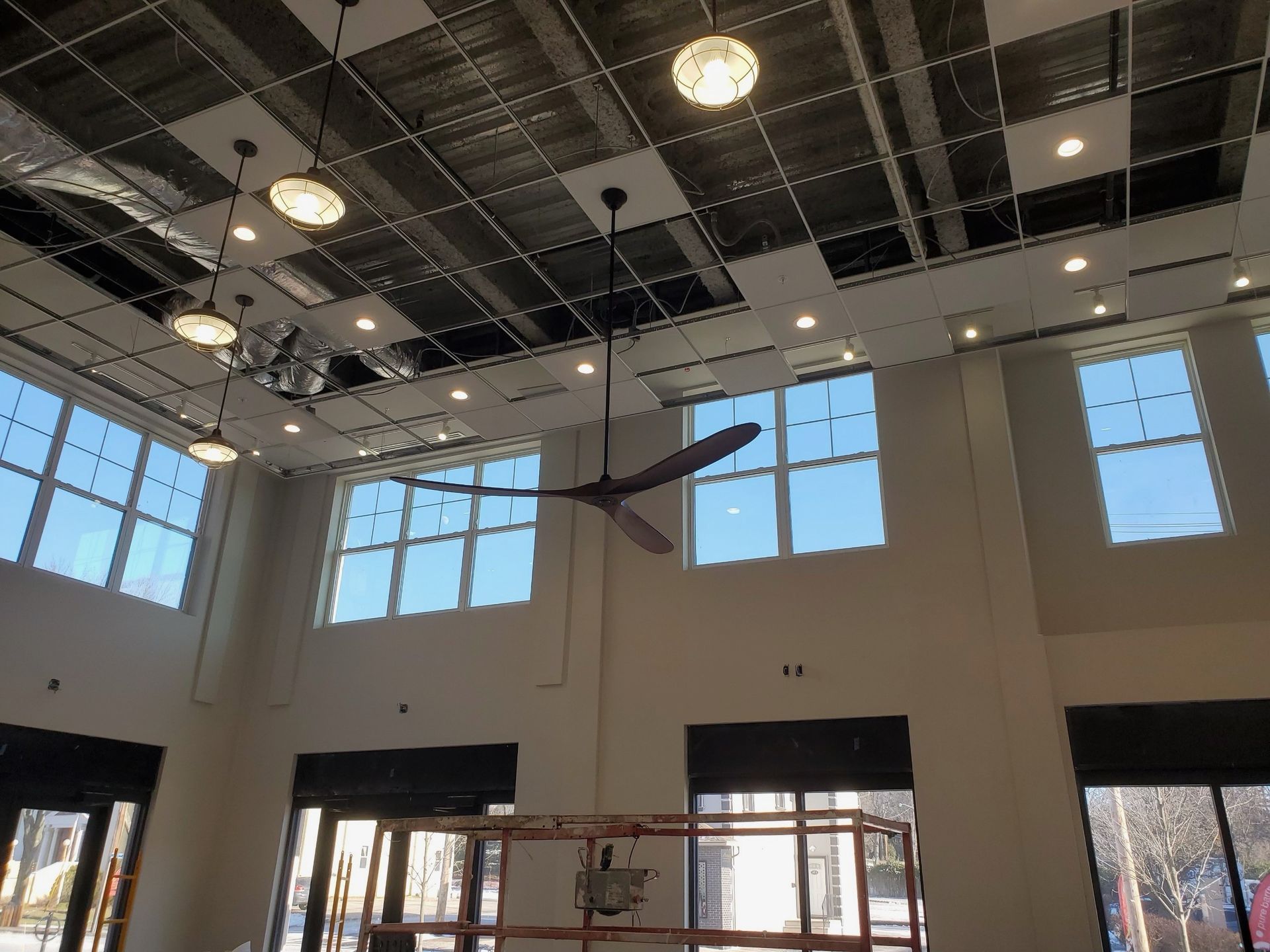 A large room with a ceiling fan and lots of windows