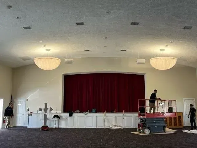 A large room with a red curtain and a man on a lift