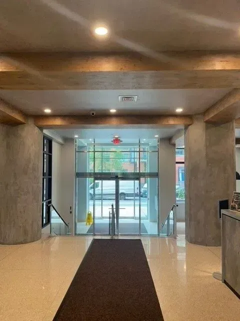 A hallway with a brown rug and a large glass door