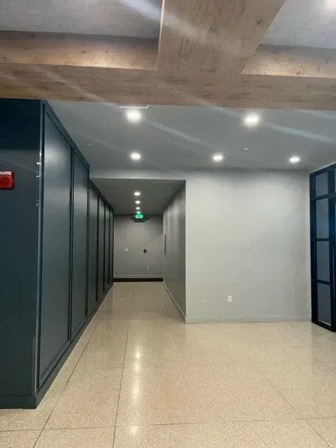 A long hallway with a green exit sign on the wall
