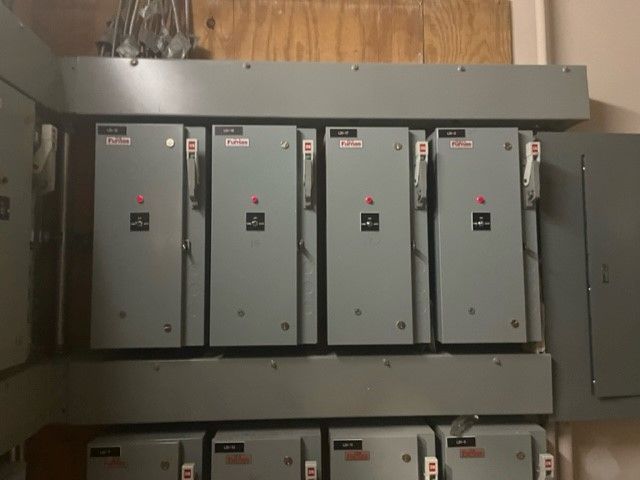 A row of electrical boxes are lined up on a wall.