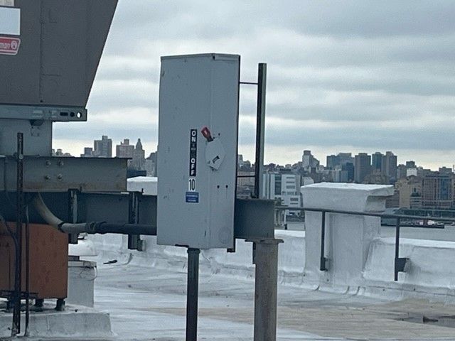A gray box on top of a roof with a city in the background