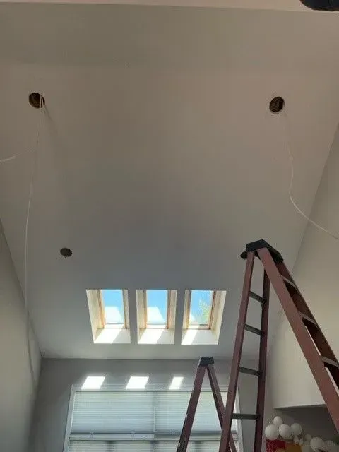 A ladder in a room with a skylight in the ceiling
