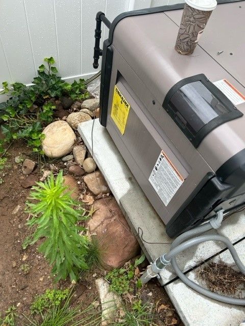 A hot tub heater is sitting on a deck next to a rocky area.