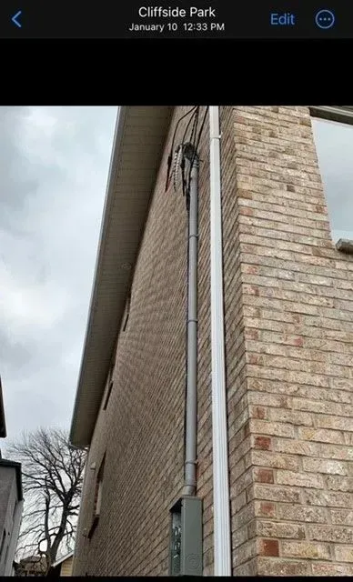 A picture of a brick house with a white pipe on the side.