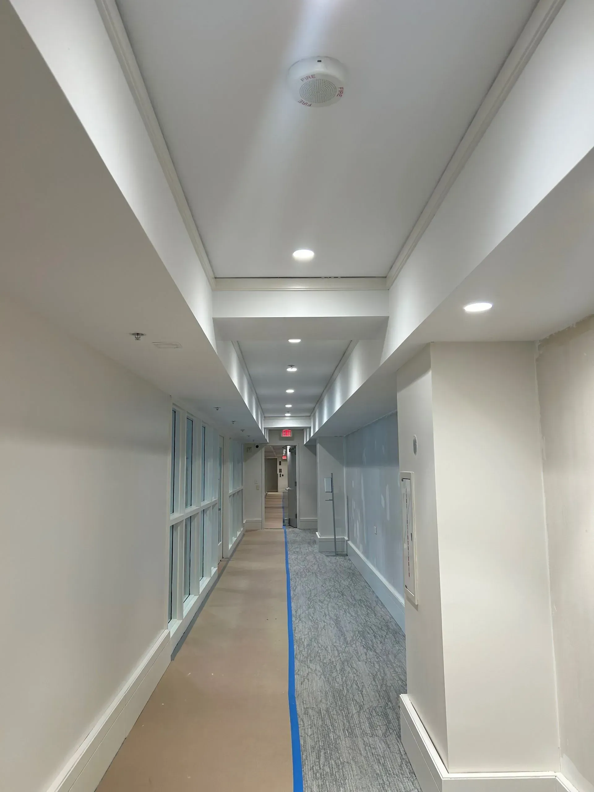 A long hallway with white walls and blue tape on the floor