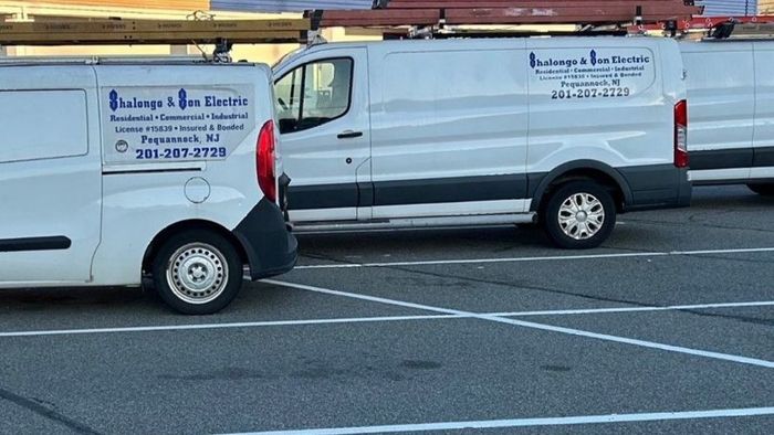 Two white vans are parked in a parking lot.