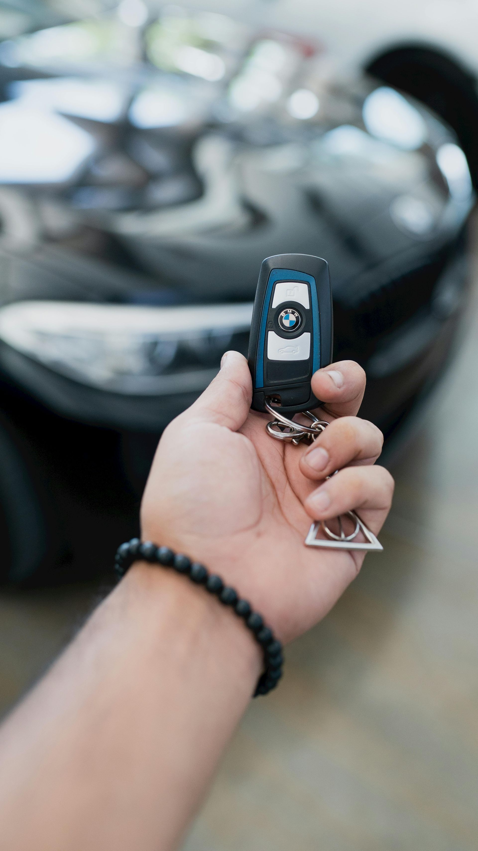 A person is holding a car key in front of a car.