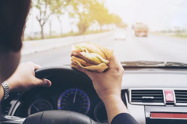 a person is eating a hamburger while driving a car