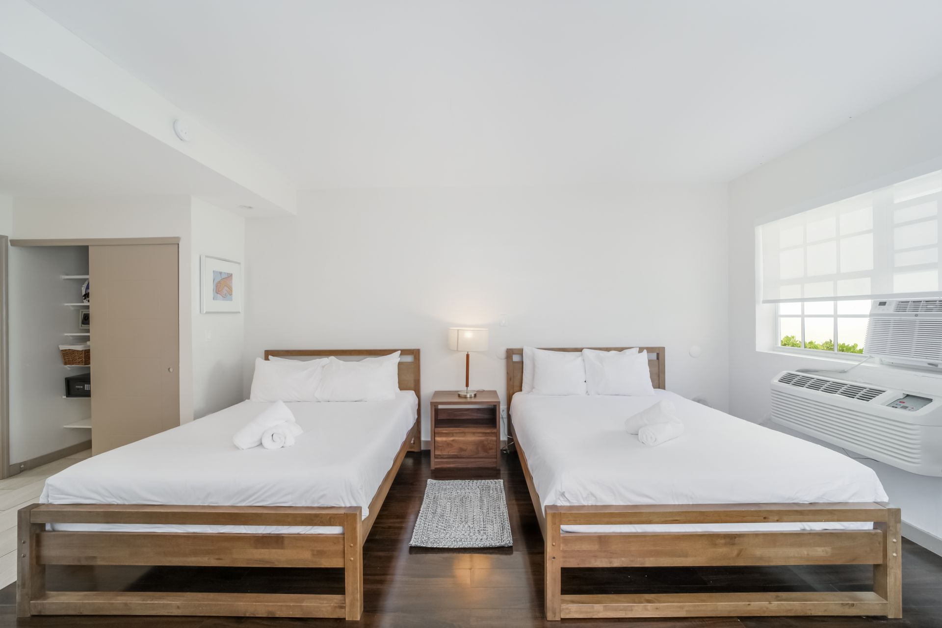 Bright bedroom with two twin beds, white walls, and a window seat by the window