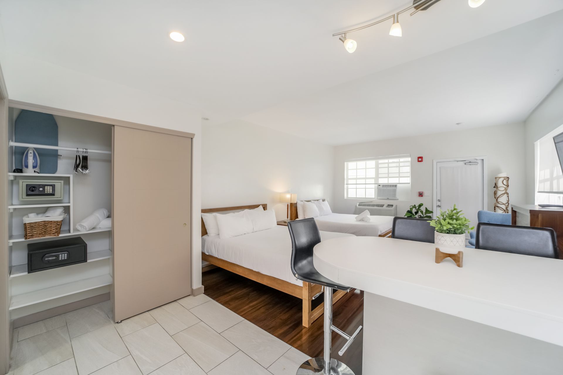 Bright open bedroom with white walls, daybed, desk, closet, and tiled floor in a modern home.