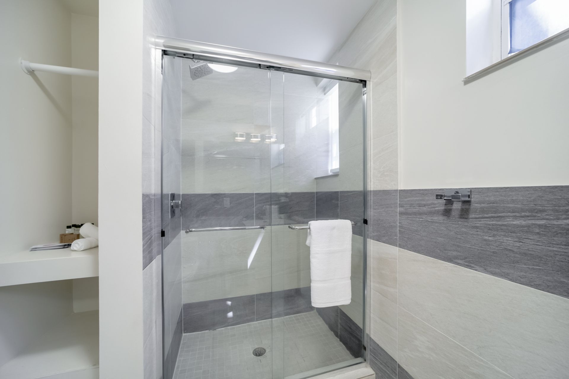 Modern bathroom with a glass shower enclosure, gray tile accents, and white walls