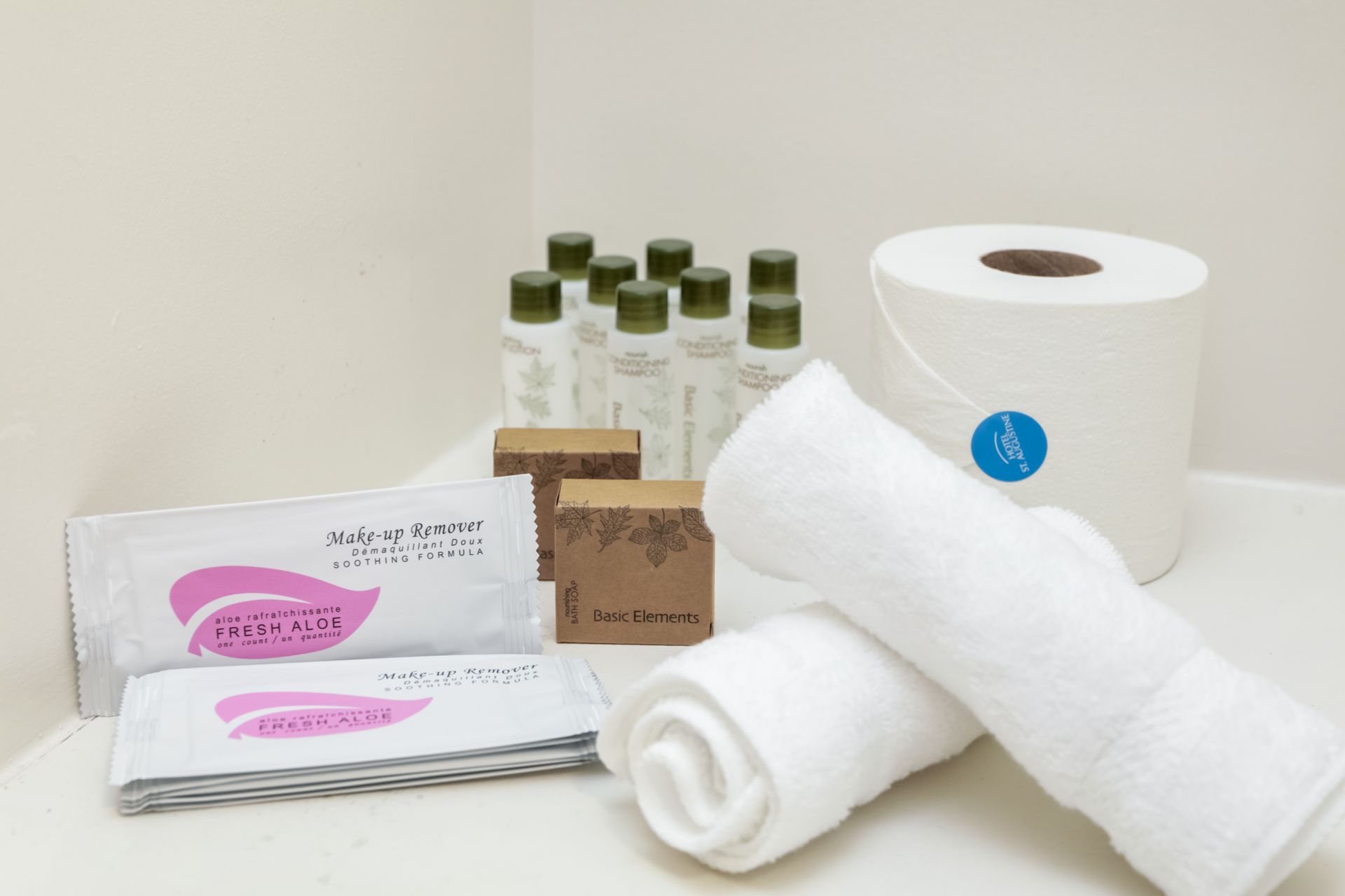 Assorted hotel toiletries and rolled white towels arranged on a countertop