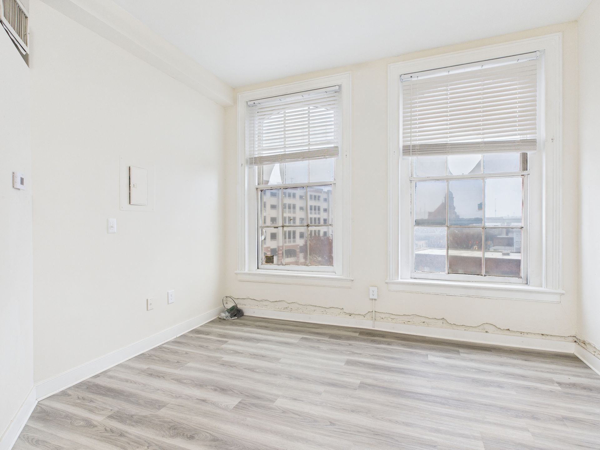 Empty room with two windows, light gray floor, and white walls.