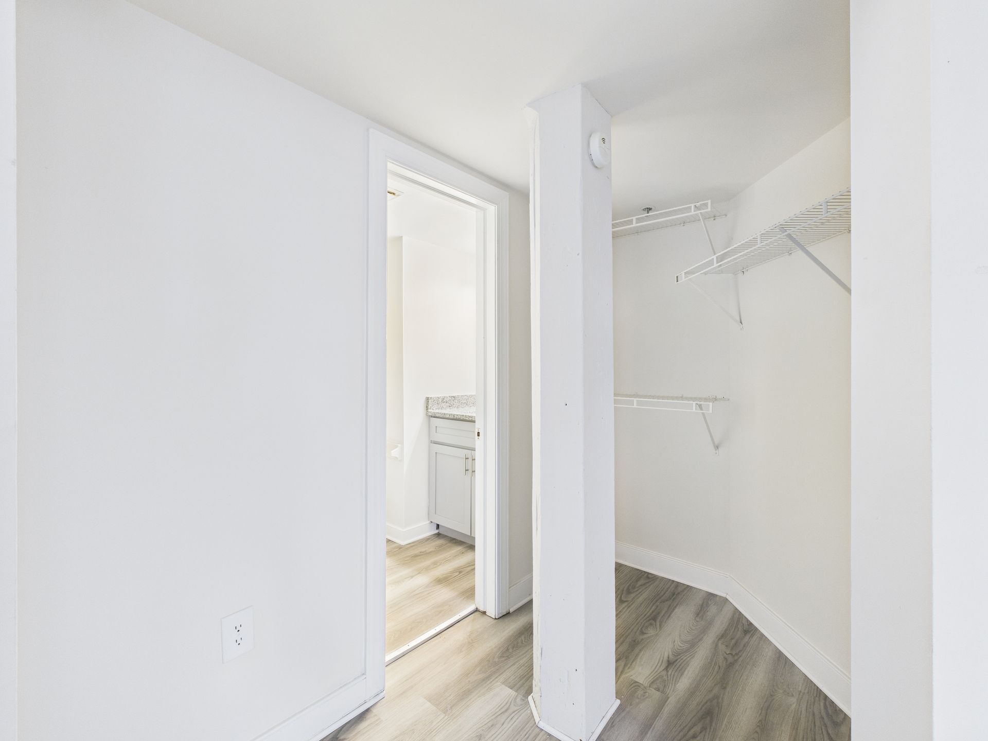 Interior view of a white-walled hallway with a closet and a bathroom visible.