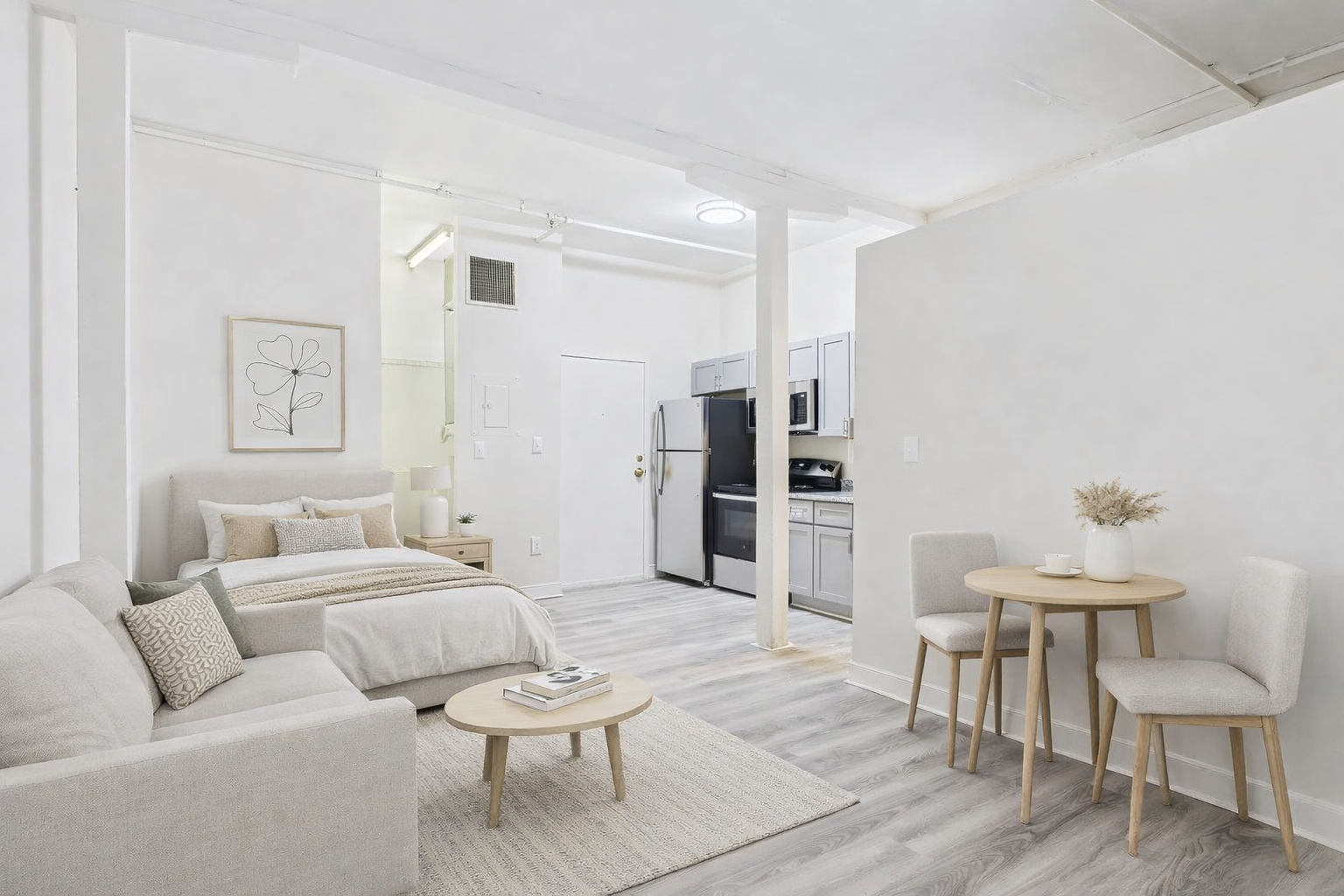 Modern, white studio apartment with living, dining, and kitchen areas; light wood floors.