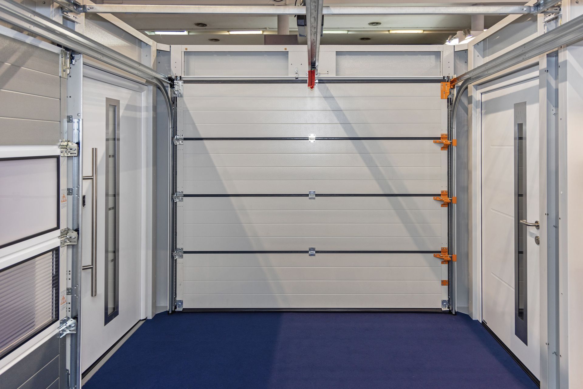 Garage interior with white walls, a closed sectional door, and a blue floor carpet