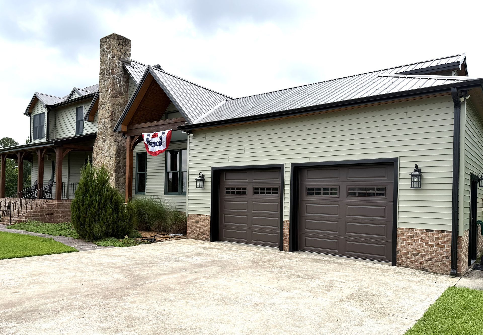 Suburban house exterior with stone chimney, double garage, and an American flag by the front door