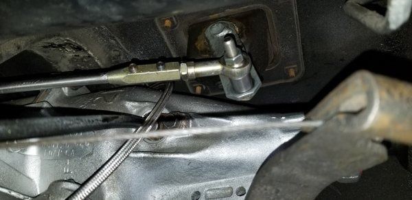 A close up of a brake pedal on a car with a hose attached to it.