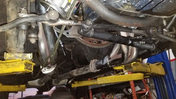 The underside of a car on a lift in a garage.