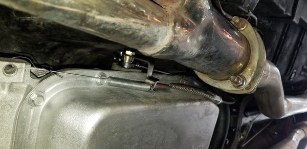 A close up of a car engine with a hose attached to it.