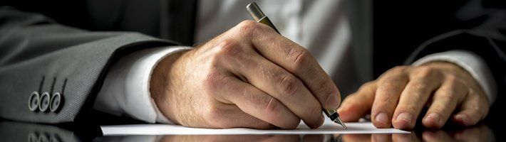 man in suit writing with a fountain pen