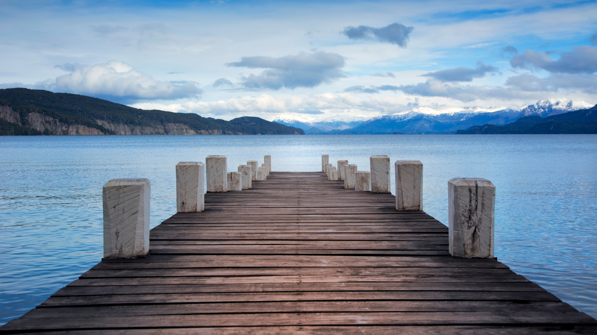 White fishing boat on blue water with a bright blue sky and wispy clouds.