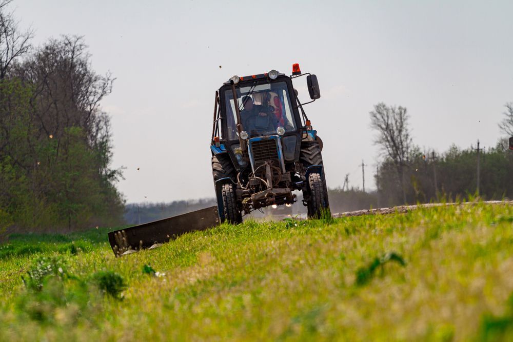 A Tractor Is Driving Down A Grassy Hill — Fewmore Contracting in Yarrawonga, NT