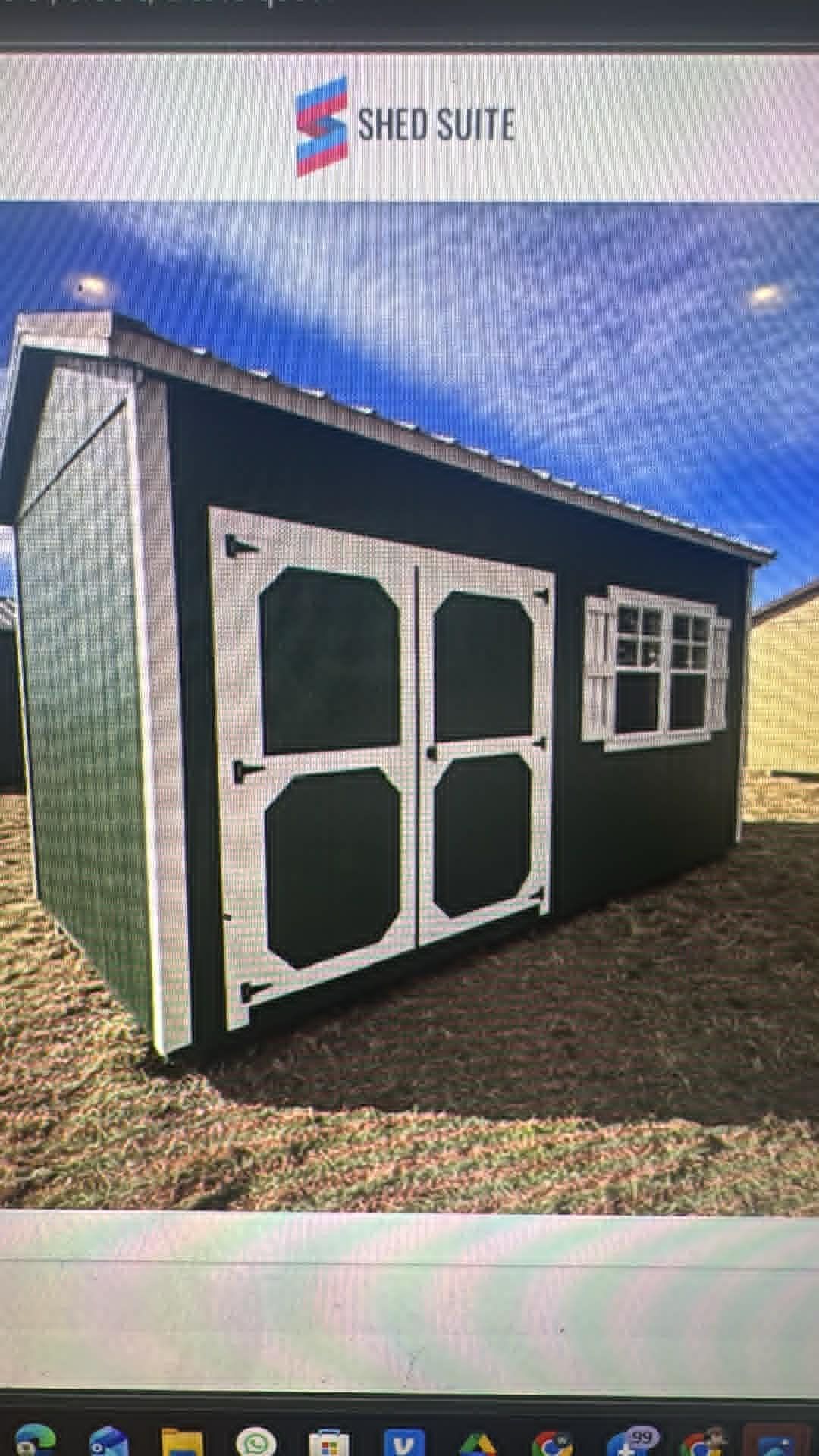 Small black-and-white shed with barn-style doors and a side window under a blue sky.