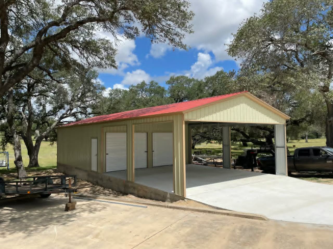 Open-sided red-roofed pavilion in a park with concrete pad, picnic tables, and trees.