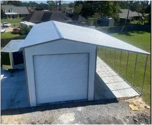 White detached garage with a closed roll-up door and a metal roof, beside a fenced concrete driveway.