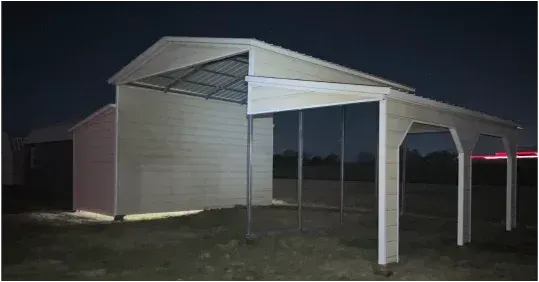 White metal carport or shed at night with open sides and a slanted roof on a grassy lot