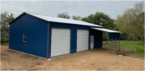 Blue metal barn with white roll-up doors and a small covered porch on a gravel lot.